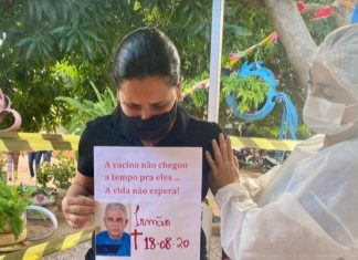 Ao se vacinar, comerciante chora e carrega fotos de mãe e irmãos que morreram pela Covid: ‘família destruída’